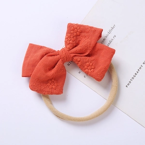 Dettaglio della fascia in cotone rosso arancio con ricamo floreale su bianco