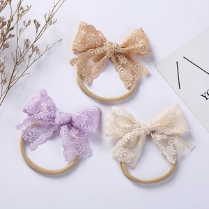 Detailed embroidery and lace texture on three assorted nylon baby headbands with bows