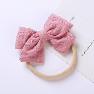 Dettaglio di fascia per capelli con fiocco rosa e ricamo su elastico in nylon