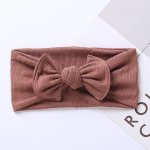Detail of brick red ribbed knit baby headband with a soft wide bow texture