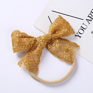 Detailed macro view of golden lace bow headband with delicate floral embroidery for babies