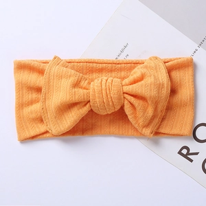 Close-up of orange ribbed knit baby headband featuring a large textured bow detail