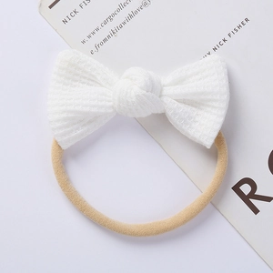 Detail of white waffle knit bow on high-elasticity nude nylon baby headband