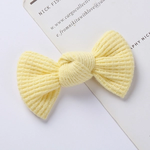 Detailed close-up of yellow knit bow hair clip with ribbed texture and soft fabric finish
