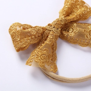 Detail of baby headband featuring gold lace floral embroidery on double layer bow