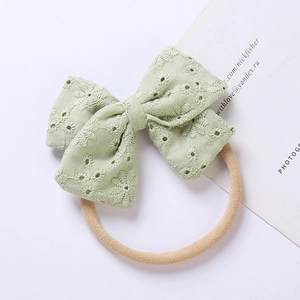 Dettaglio fascia per neonati con fiocco ricamato verde chiaro ed elastico in nylon