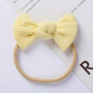 Close-up of yellow waffle knit baby headband with elastic band and decorative bow tie