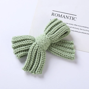 Détail du nœud papillon tricoté vert clair présentant une texture en laine et design doux