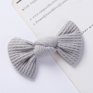 Detailed macro shot of a light gray ribbed knit bow hair clip for children with soft texture
