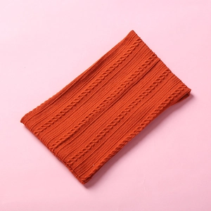Detailed knit texture of a warm orange winter neck warmer on a pink background