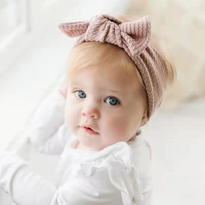 Detail of baby headband featuring soft pale pink waffle knit fabric and a large bow