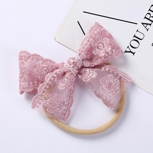 Close-up of pink lace embroidery bow with soft nylon headband for infant girls