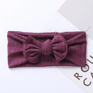 Detail of dark purple knitted baby headband with large jacquard bow and ribbed texture
