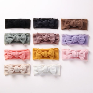 Flat lay of ribbed fabric baby headbands with large bows in eleven assorted colors