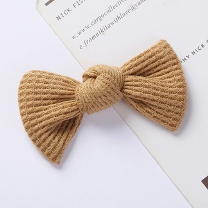 Detailed view of a khaki waffle-knit bow hair clip with fine ribbed texture on a white card