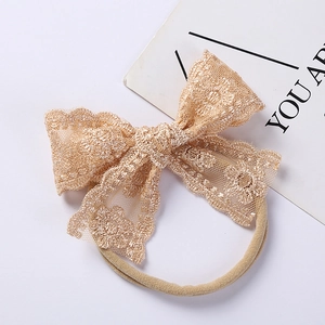Detail of champagne lace bow headband with delicate floral embroidery for babies