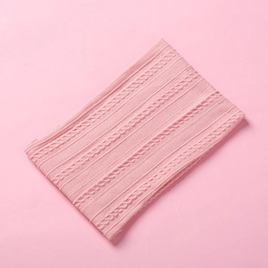 Detail shot of pink knitted baby headband showing intricate cable knit and ribbed texture
