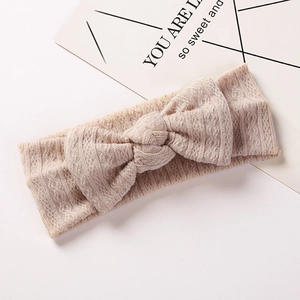 Détail du bandeau bébé avec texture jacquard et nœud en tricot de couleur beige