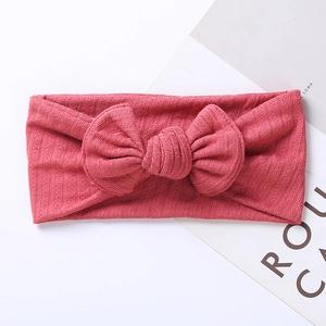 Detailed close-up of coral pink ribbed fabric baby headband with a large bow decoration