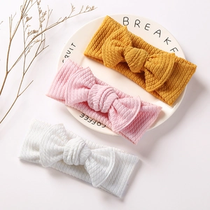 Detailed texture of knitted baby headbands with large bows in yellow, pink and white