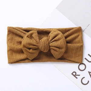Detailed texture of mustard yellow ribbed knit baby headband with a large bow decoration