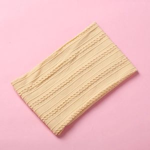 Close-up of beige jacquard knit baby headband with soft cable pattern texture