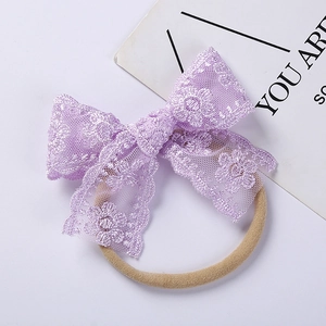 Close-up of soft purple floral lace embroidery bow on an elastic baby headband