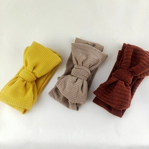 Detailed texture of three waffle knit bow headbands in ginger, coffee, and brick red
