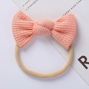 Detailed close-up of pink peach baby headband featuring soft waffle knit bow texture