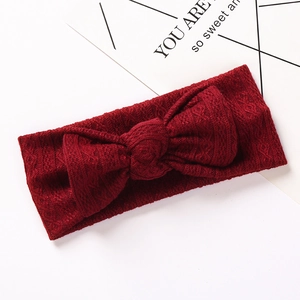 Gros plan sur la texture jacquard rouge foncé du bandeau élastique à nœud pour bébé