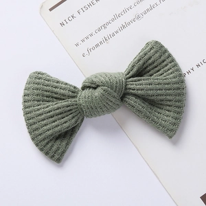 Detailed close-up of sage green waffle knit bow hair clip with ribbed texture on card