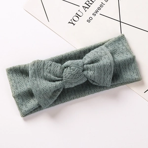 Détail d'un bandeau bébé en maille côtelée vert sauge avec un grand nœud décor