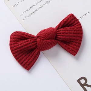 Close-up detail of dark red waffle knit bow hair clip with thick textured knit fabric