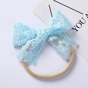 Close-up of light blue lace bow headband with delicate floral embroidery for infants