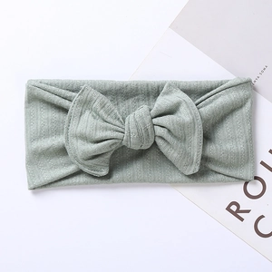 Detailed texture of mint green ribbed knit fabric baby headband with large bow accent