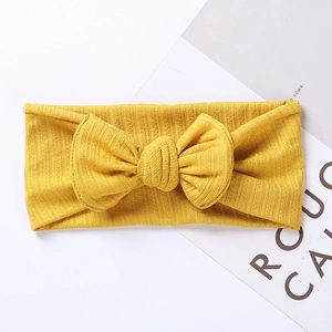 Detailed texture of ginger yellow ribbed knit baby headband with a large bow decoration