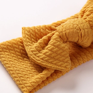 Close-up of ginger yellow waffle knit texture and bow detail on an infant headband