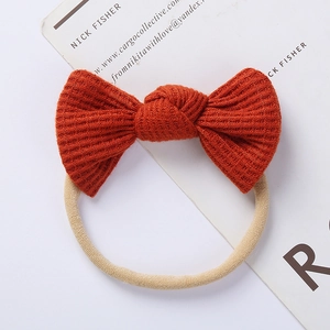 Detail of the orange waffle knit bow headband with elastic nude nylon band for babies