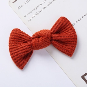 Macro view of rust red waffle knit bow hair clip showing detailed ribbed texture on card