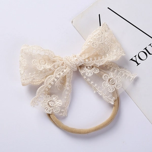 Detailed macro view of cream lace bow headband with intricate embroidery and soft nylon strap