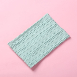 Close-up of mint green cable-knit baby headband showing soft ribbed texture on pink background