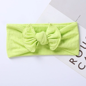 Detail of neon green ribbed knit baby headband featuring a large textured bow design