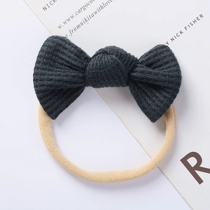 Detailed close-up of dark green waffle knit bow headband with elastic nude band