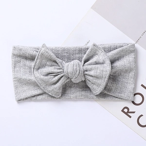 Close-up of gray ribbed knit baby headband featuring a large bow on white background