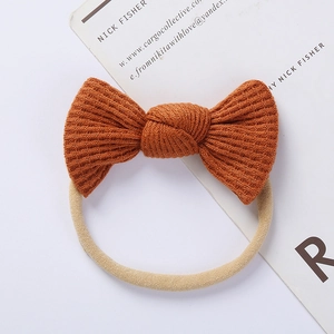 Detail of orange-brown waffle knit bow on seamless elastic nylon headband for babies
