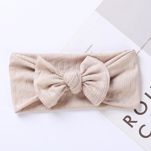 Detailed macro view of the knitted rib fabric and oversized bow on the beige baby headband