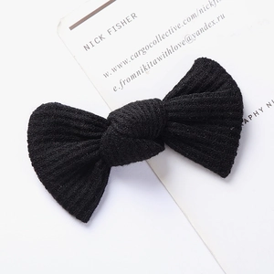 Detailed view of black knitted bow hair clip showing premium ribbed waffle texture