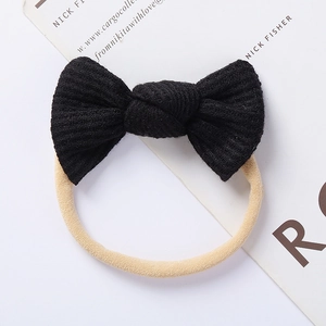 Detail of baby headband with black waffle knit bow and soft nude nylon elastic band