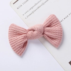 Close-up of pink waffle knit bow hair clip with textured fabric for baby girls