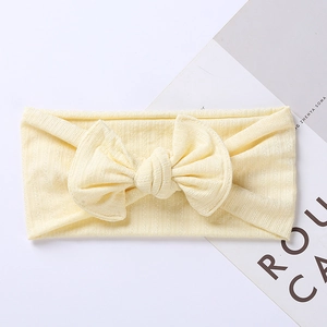 Detail of light yellow knitted baby headband with a jacquard bow on a white background